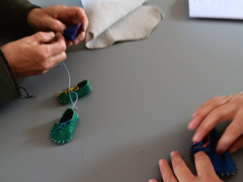 Détail des mains coupant du cuir pendant un atelier de fabrication de mini-chaussures pour un team building à Romans-sur-Isère.