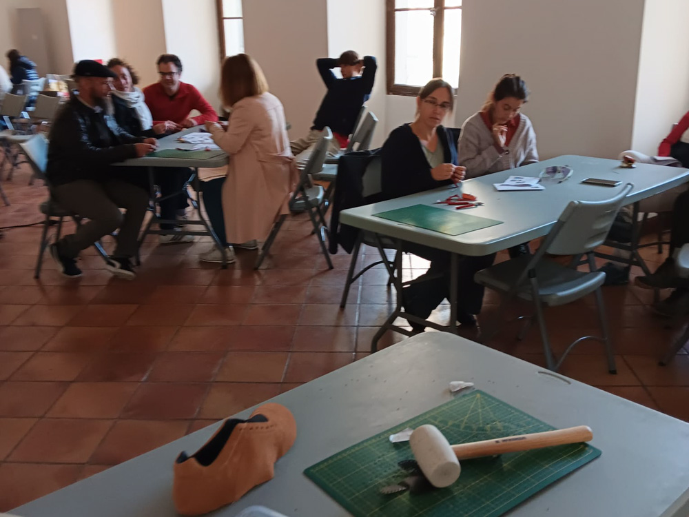 Ambiance conviviale : collègues échangeant pendant un atelier de fabrication de mini-chaussures en cuir à Romans-sur-Isère