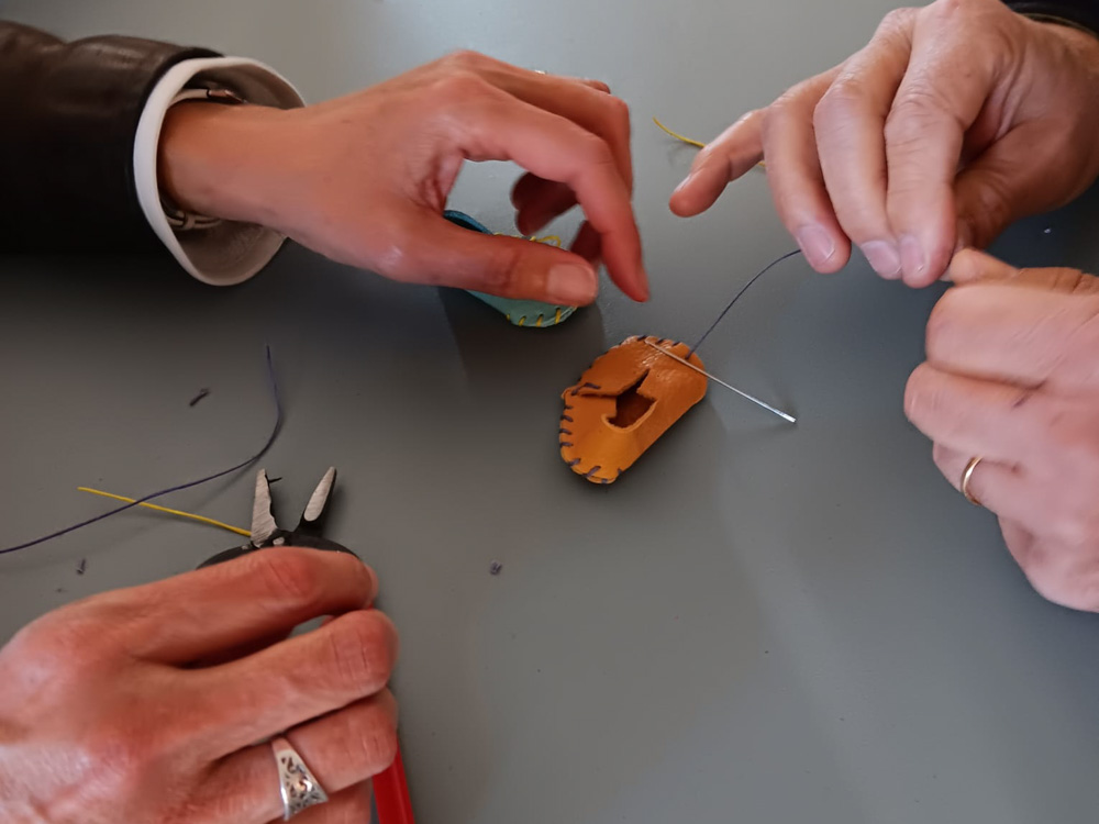 Détail des mains coupant du cuir pendant un atelier de fabrication de mini-chaussures pour un team building à Romans-sur-Isère